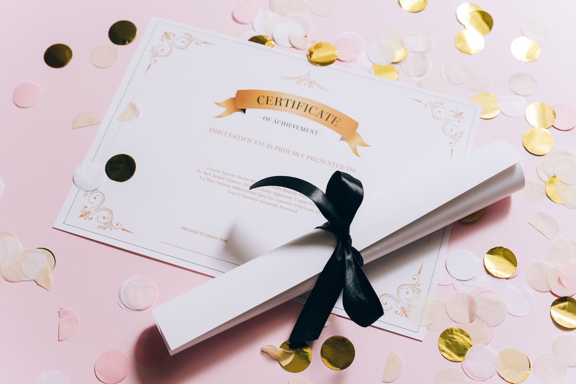 rolled white paper and a certificate on a pink surface